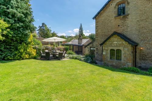 een tuin met een stenen huis met een parasol bij Colebrook Cottage in Blockley