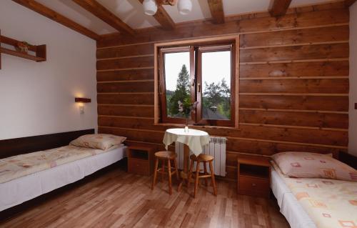 a room with two beds and a table and a window at Pensjonat Lesniczówka bieszczady solina polańczyk in Polańczyk
