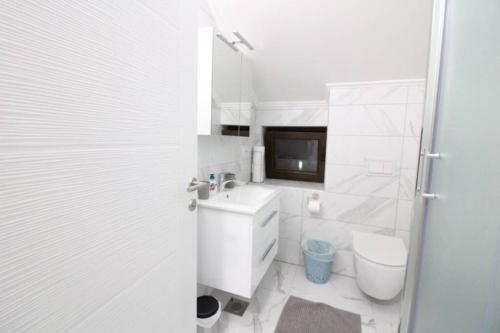 a white bathroom with a toilet and a sink at WATERFRONT VILLA SUNSET DREAM WITH POOL in Trebinje