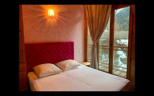 a bedroom with a bed with a red headboard and a window at Mont Blanc in Peisey-Nancroix