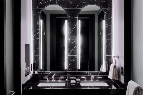a black bathroom with two sinks and two mirrors at Daxton Hotel Birmingham, Curio Collection by Hilton in Birmingham