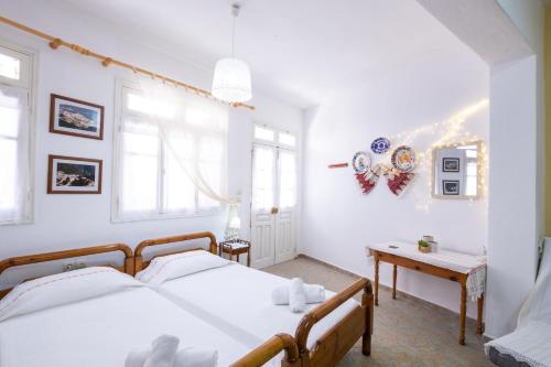 a white bedroom with two beds and a table at Sellai House in Olympos