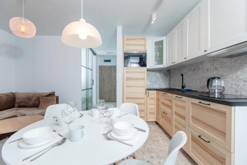 eine Küche mit einem weißen Tisch und Stühlen in einem Zimmer in der Unterkunft Resort Apartamenty Klifowa Rewal 59 in Rewal