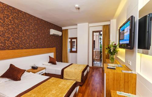 a hotel room with two beds and a flat screen tv at Eftalia Down Town in Alanya