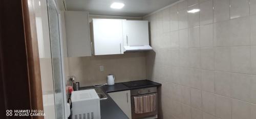 a small bathroom with a sink and white cabinets at Quarto vista mar in Câmara de Lobos