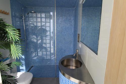 a bathroom with a sink and a shower with blue tiles at Hostal Fornet Altea in Altea