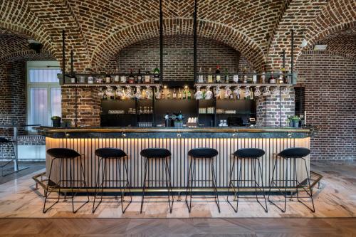 a bar with stools in a room with a brick wall at Mercure Liege City Centre in Liège