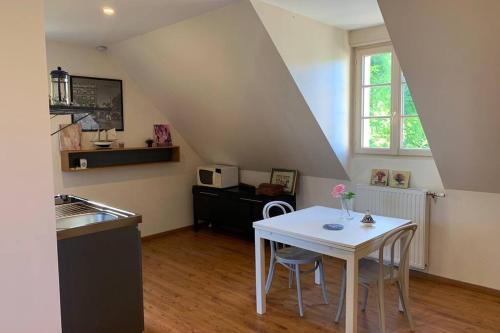 - une cuisine avec une table et des chaises blanches dans la chambre dans l'établissement Studio indépendant dans maison neuve, à Senlis