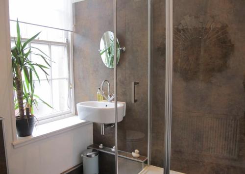 a bathroom with a shower with a sink and a mirror at Royal Mile Apartment in Edinburgh