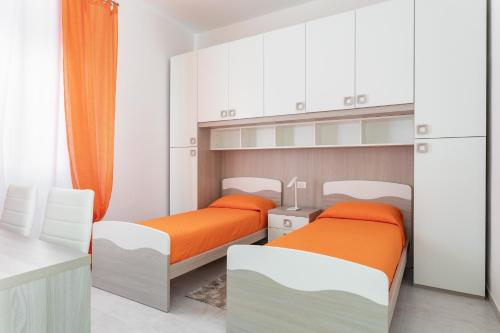 CASA L'ANGOLO FIORITO في كابراس: سريرين في غرفة بها دواليب بيضاء وملاءات برتقالية