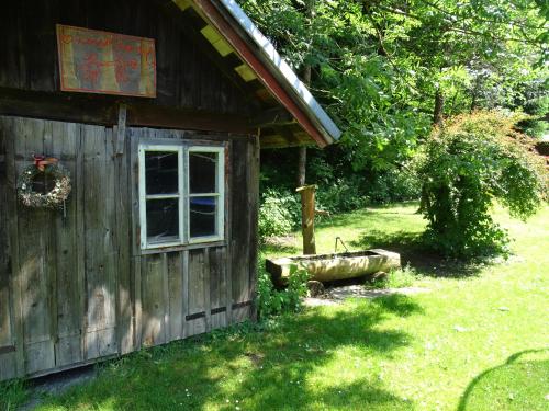 a wooden cabin with a window and a tub outside at Pension Bayrhammer in Faistenau