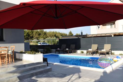 - un parasol rouge assis à côté de la piscine dans l'établissement B1villa, à Srima