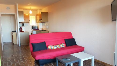 - un canapé rouge dans le salon avec une table dans l'établissement CYSTES, à Kamiesch