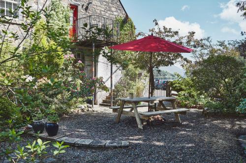 a picnic table with a red umbrella and a bench at Brambles of Inveraray in Inveraray
