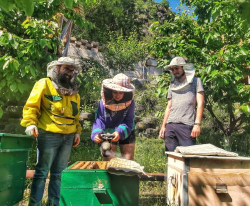 a group of people wearing hats standing next to a container at ARMBEE Honey Farm in Alaverdi
