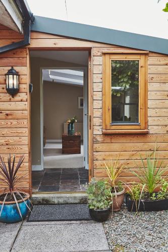 an open door of a wooden house with potted plants at Brambles of Inveraray in Inveraray