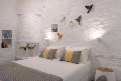 Dormitorio blanco con cama y pared blanca en NIREAS STONEHOUSE IN APOLLONIA SIFNOS, en Sifnos