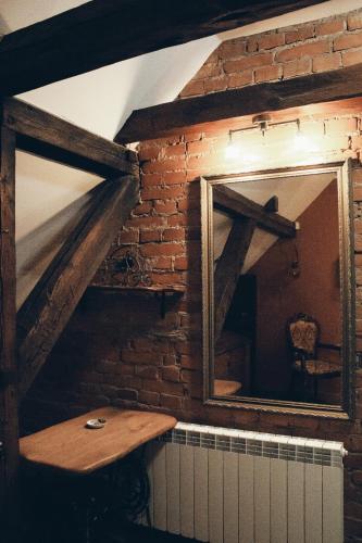 a mirror on a brick wall with a wooden table at Mõisa Ait Katusekorter in Võru
