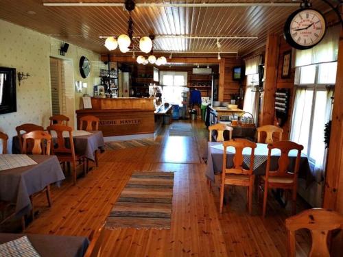 un restaurant avec des tables et des chaises et une horloge sur le mur dans l'établissement Kuortane Kuharanta, à Mäyry