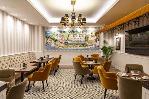 屈赫隆斯博爾恩的住宿－歐羅巴庫蘭斯伯恩酒店，餐厅设有桌椅,墙上挂有绘画作品