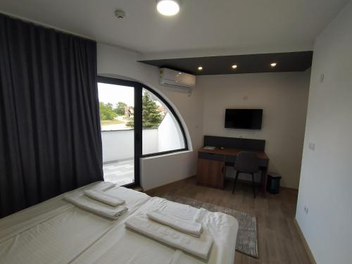 1 dormitorio con cama, escritorio y ventana en Prenoćište Srebrno Jezero en Veliko Gradište