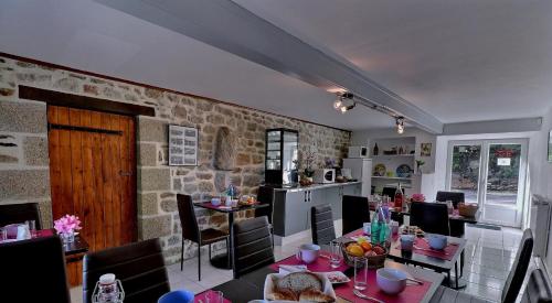une cuisine et une salle à manger avec un mur en pierre dans l'établissement Chambres d'Hôtes Les Fleurettes en Baie Du Mont Saint Michel, à Saint-Marcan
