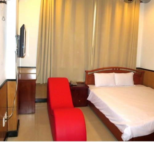 ダナンにあるNHÀ NGHỈ MINH NHIのベッドと赤い椅子が備わるホテルルームです。