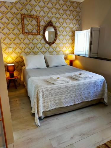 een slaapkamer met een bed en een spiegel aan de muur bij Nas Três Janelas in Viana do Castelo