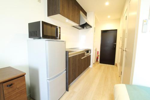 a small kitchen with a refrigerator and a microwave at Bears Stay Kumejima Eef Beach in Kumejima