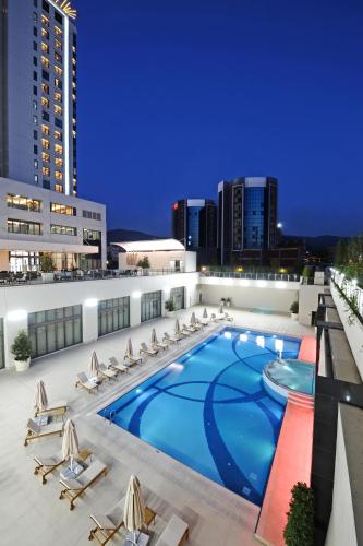 a swimming pool on the roof of a building with chairs at Crowne Plaza Bursa Convention Center & Thermal Spa by IHG in Bursa