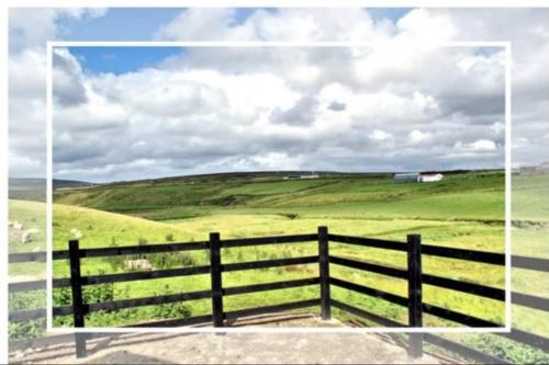 a fence with a green field and a cloudy sky at Cozy & Remote Hideaway Gintys Cottage in Ross Port