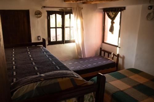 a bedroom with two beds and two windows at Tierra Andina Hostel in Tilcara