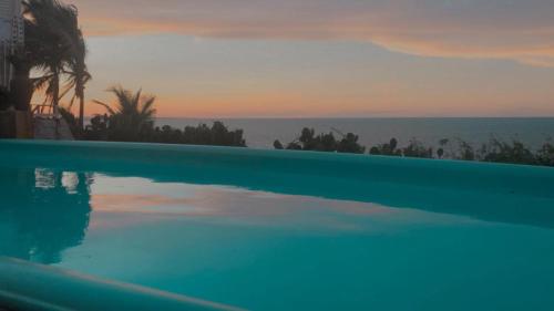 a large swimming pool with a view of the ocean at Pousada Azul Marinho in Canoa Quebrada