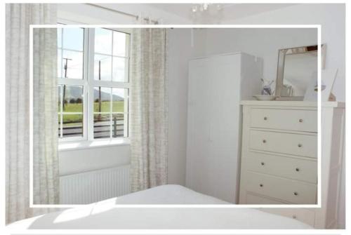 a white bedroom with a dresser and a mirror at Cozy & Remote Hideaway Gintys Cottage in Ross Port
