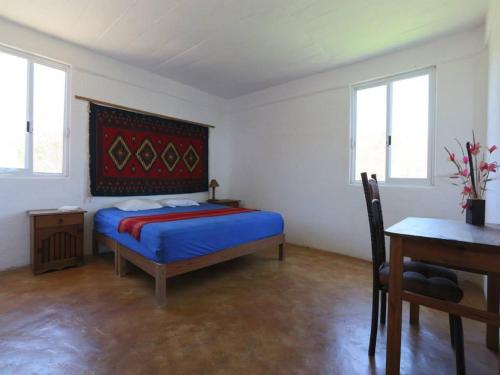 a bedroom with a bed and a table and windows at Casa Macondo in Puerto Ángel