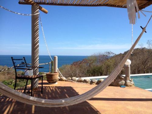 a hammock on a porch with a view of the ocean at Casa Macondo in Puerto Ángel