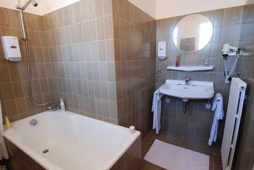 uma casa de banho com um lavatório, uma banheira e um espelho. em Logis Hôtel Restaurant de France em Saint-Geniez-dʼOlt