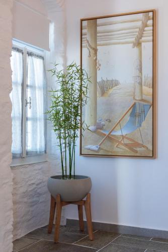 a plant in a vase next to a picture on a wall at NIREAS STONEHOUSE IN APOLLONIA SIFNOS in Sifnos