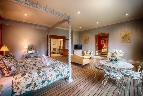 a bedroom with a canopy bed and a living room at Miskin Manor Hotel in Hensol