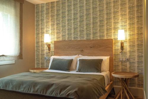 a bedroom with a large bed with two tables at Apartamentos Boutique Fuente Real in Comillas