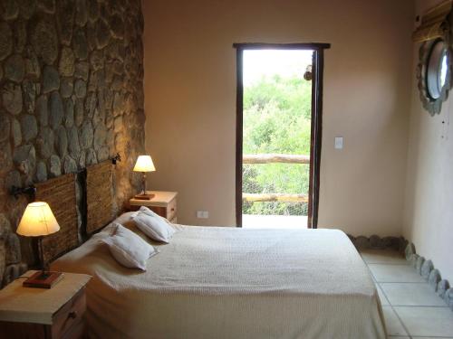 Un dormitorio con una cama grande y una ventana en Cabañas en Piedras Maia en Merlo