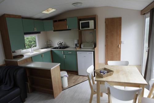 una pequeña cocina con armarios verdes y una mesa en CHALET AAN HET STRAND, en Nieuwvliet