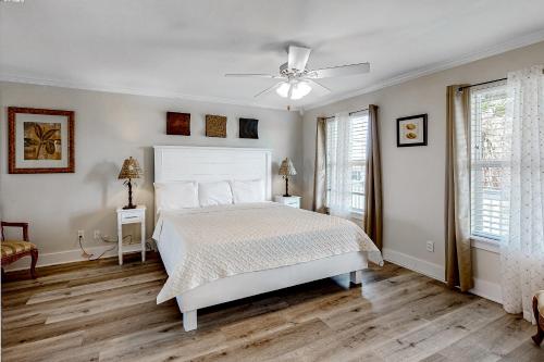 1 dormitorio con cama blanca y ventilador de techo en Malibu Beach House en Dauphin Island