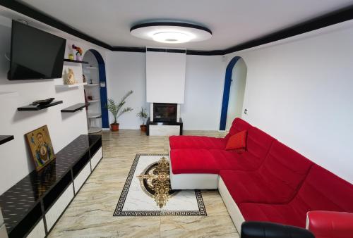 a living room with a red couch and a tv at Apartament Mara in Jurilovca