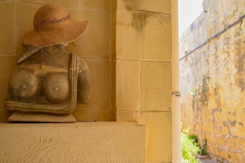 a statue with a straw hat sitting on a wall at Villa Xini in Xewkija