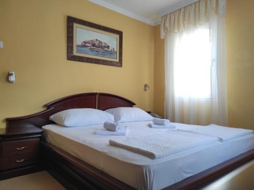 een slaapkamer met een bed met witte lakens en een raam bij Hotel Mimoza in Budva