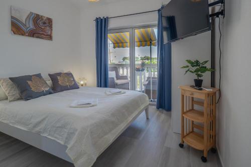 a bedroom with a bed and a television and a balcony at Apartments Domic in Banjole