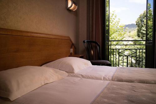 a bedroom with two beds and a window with a view at Logis Hôtel Restaurant Le Mont Aigoual in Meyrueis