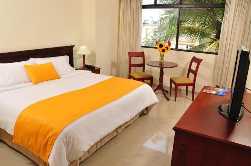 a bedroom with a bed and a desk with a television at Hotel Faranda Express Puerta Del Sol Barranquilla, A Member of Radisson Individuals in Barranquilla