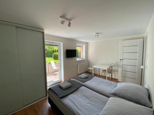 a bedroom with a large bed and a table and a window at Dwa osobne pokoje z kuchnią i łazienką na wyłączność- niedaleko plaży in Gdynia